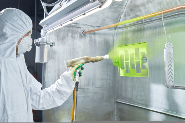 Person spray coating aluminium on a rack